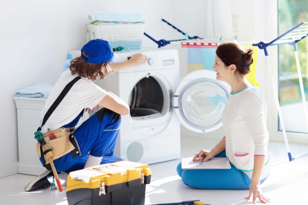 a technician repairing a washer while woman is watching - appliance repair service Staten Island
